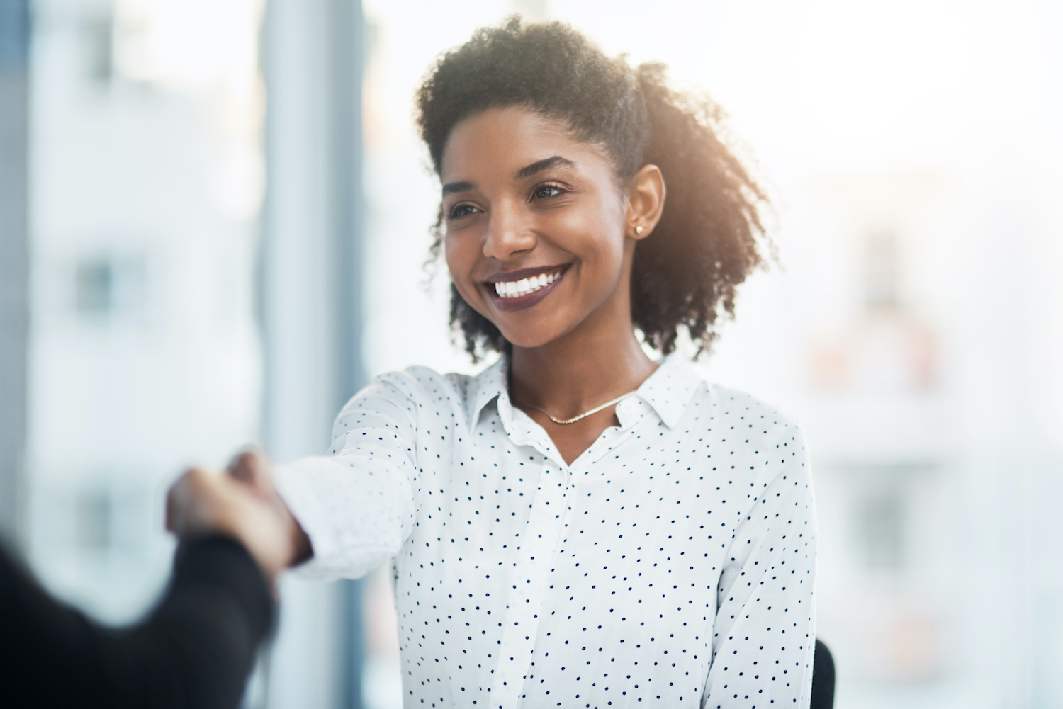 A happy young business woman shaking hands with a work colleague.